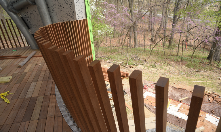 Wooden pickets at the rear of the Chrysalis, forming guard rails for the stage. (Click for a higher-resolution version.)  The perforated aluminum sheets in the background cover and protect the ZEPPS panels closest to the stage floor. Image © 2017 Living Design Lab; used with permission.